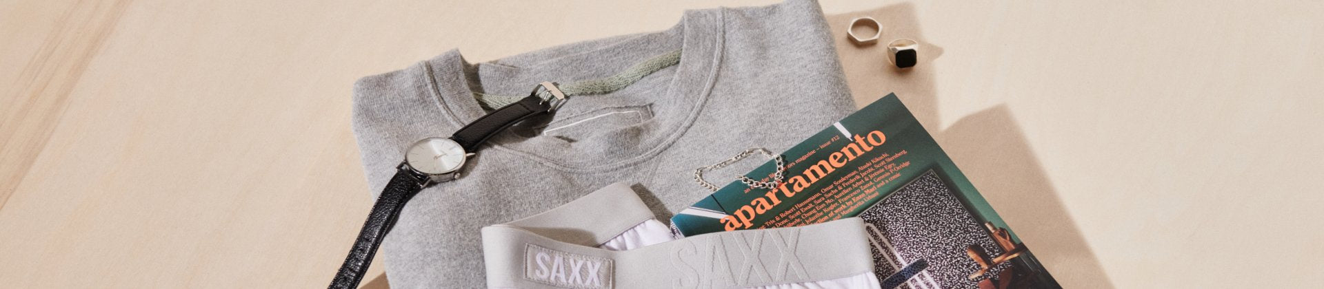 Grey sweatshirt tucked amongst watch and magazine