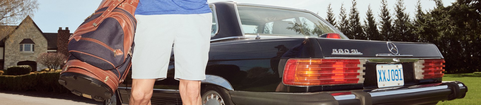 Man with golf bag standing next to vehicle at gold course