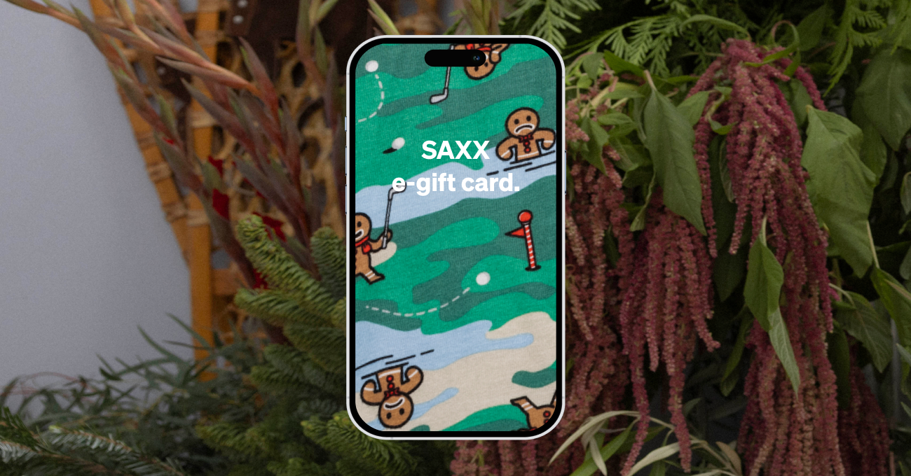 A phone screen with green camo print and gingerbread men playing golf, reading “SAXX e-gift card” with winter greenery in back.