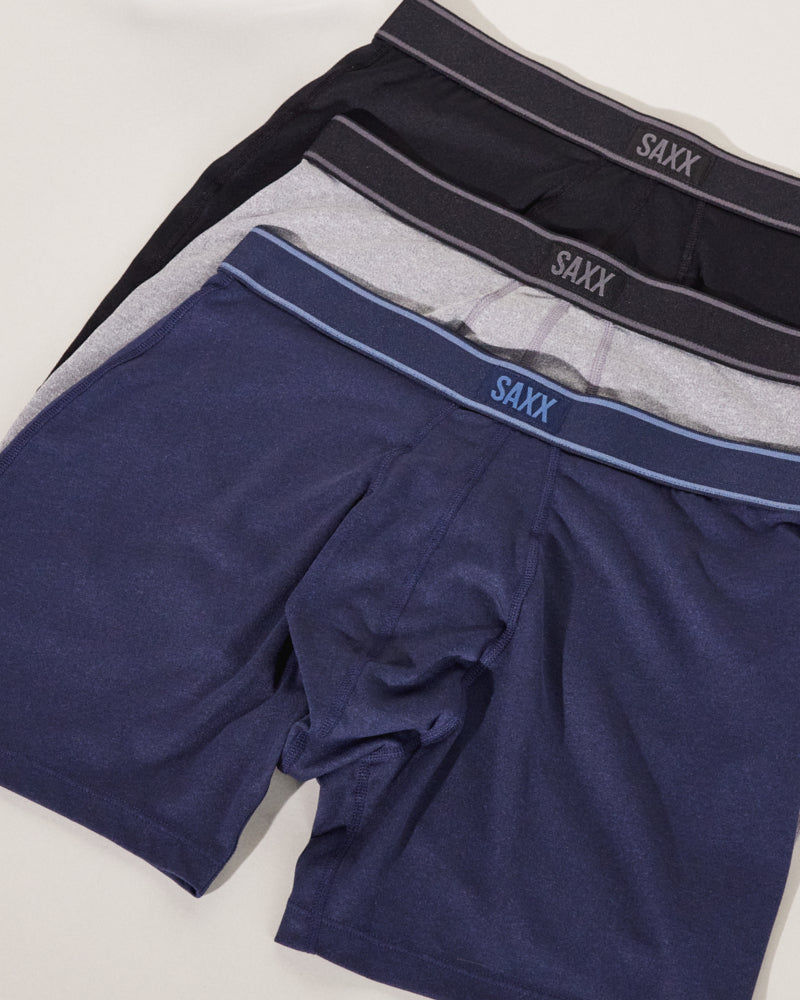 Three pairs of boxer briefs staggered on top of each other. They are colored blue, grey, and black respectively