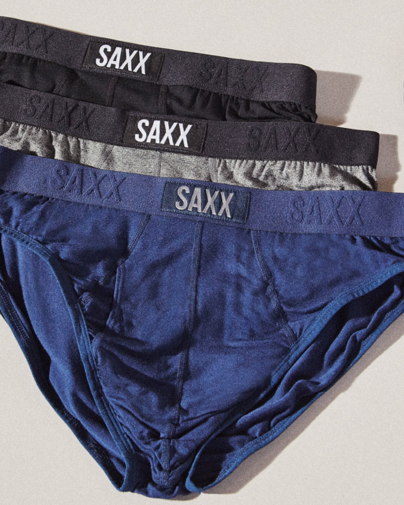 Three pairs of briefs staggered on top of each other. They are colored blue, grey, and black respectively