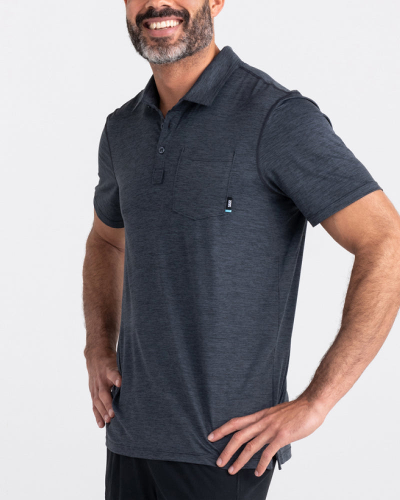 A close up of a man wearing a dark grey polo shirt. He has his hands on his hips.