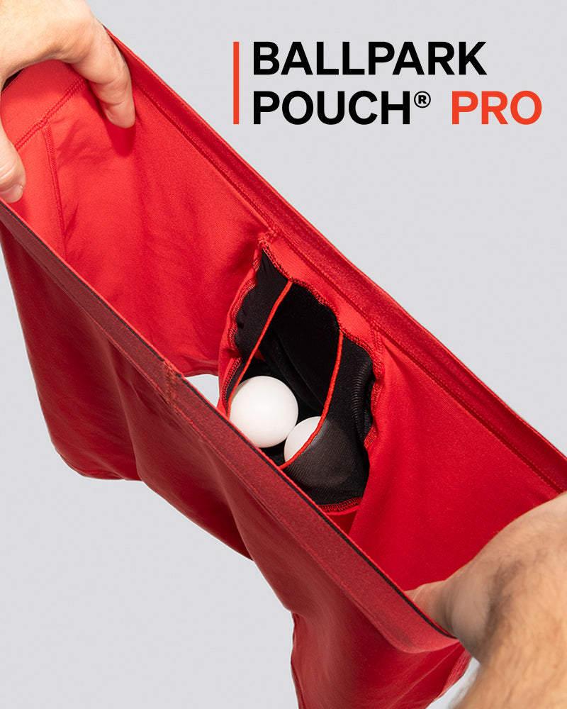 The inside of a red pair of underwear being held open to reveal a pouch with two ping pong balls inside.