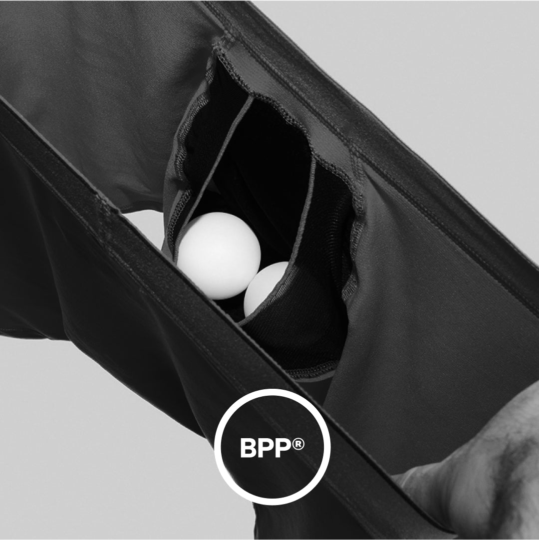 Closeup on interior view of SAXX Boxer Briefs holding two ping pong balls in the pouch. White icon indicates BallPark Pouch®.