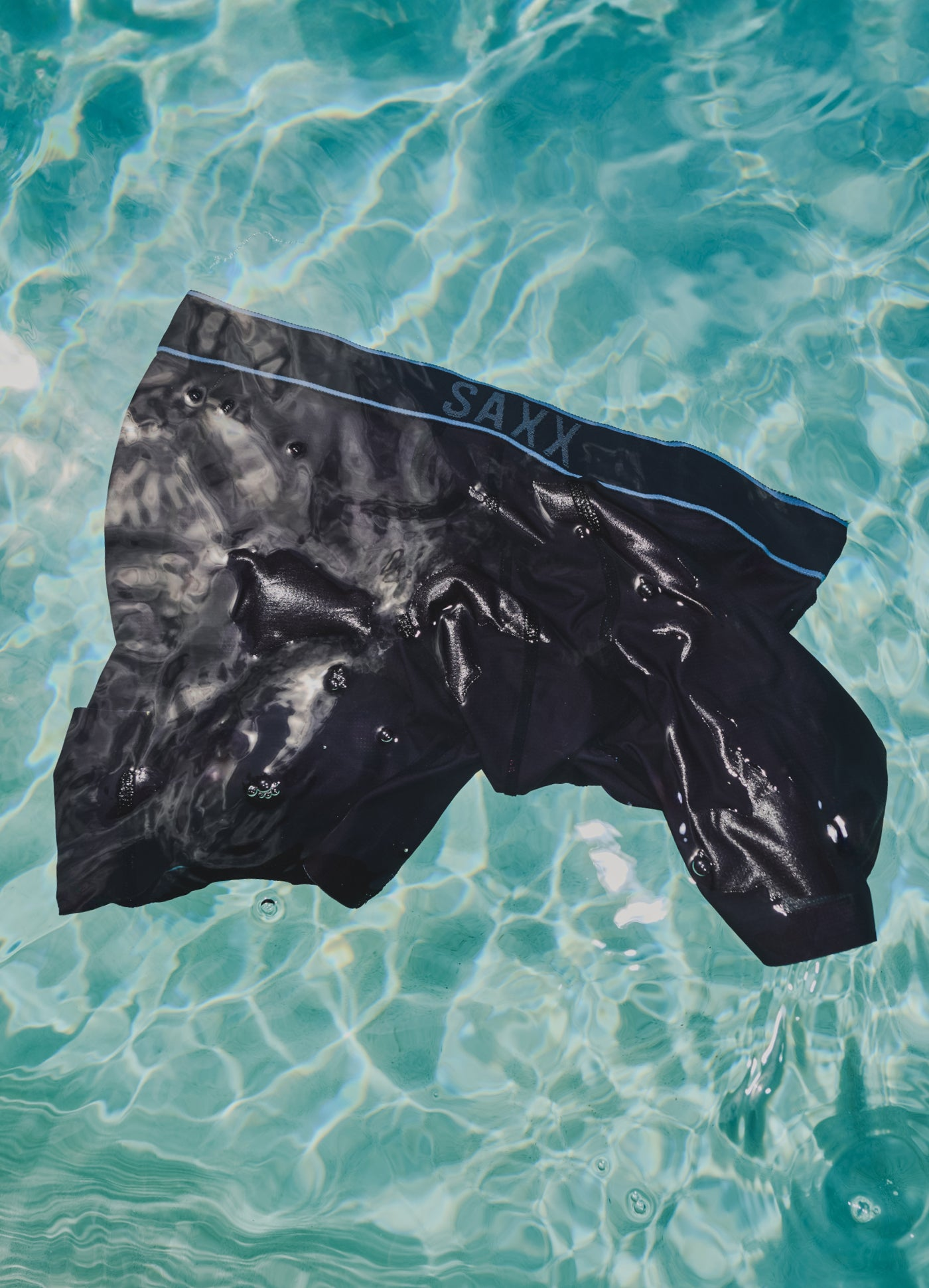 A pair of black mesh boxer briefs floating in water. 