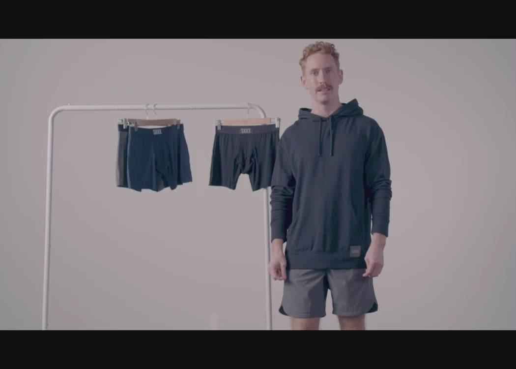 Video of a man standing in front of a clothing rack, where various SAXX Underwear featuring the BallPark Pouch hang