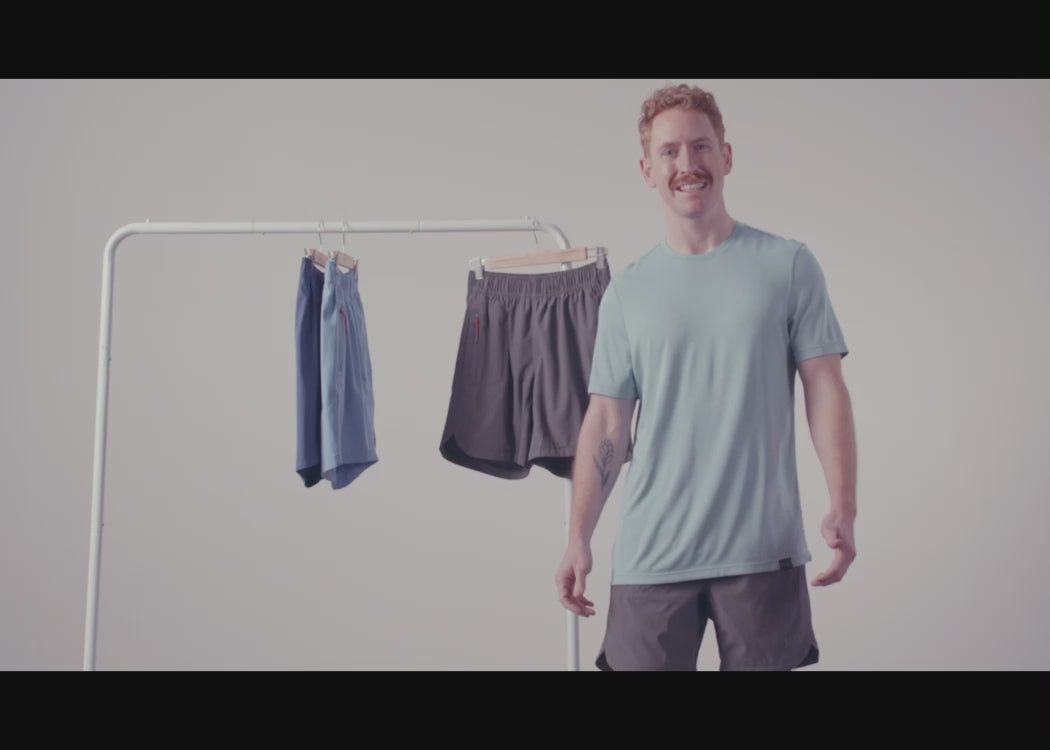 A man standing in front of various colourways of the Gainmaker short, hanging on a clothing rack.