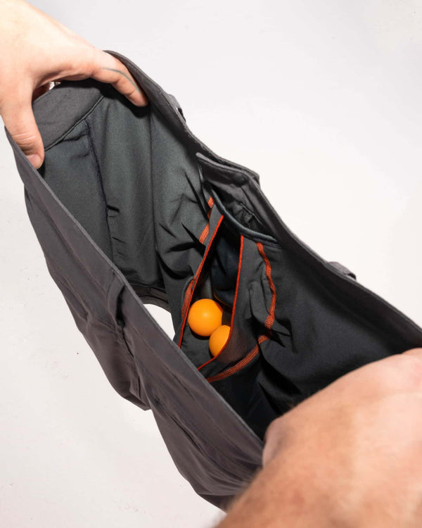 Man's hands revealing inside of 2N1 shorts showing liner with pouch holding two ping pong balls